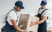 Dois homens carregando caixas de mudanças em dias chuvosos