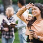 Estudante sorri em campus universitário, pautando o desafio de mudar de cidade para estudar.