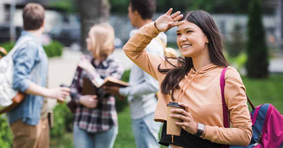Estudante sorri em campus universitário, pautando o desafio de mudar de cidade para estudar.